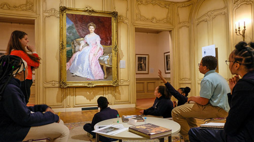 a group of school children explore an art museum with an educator