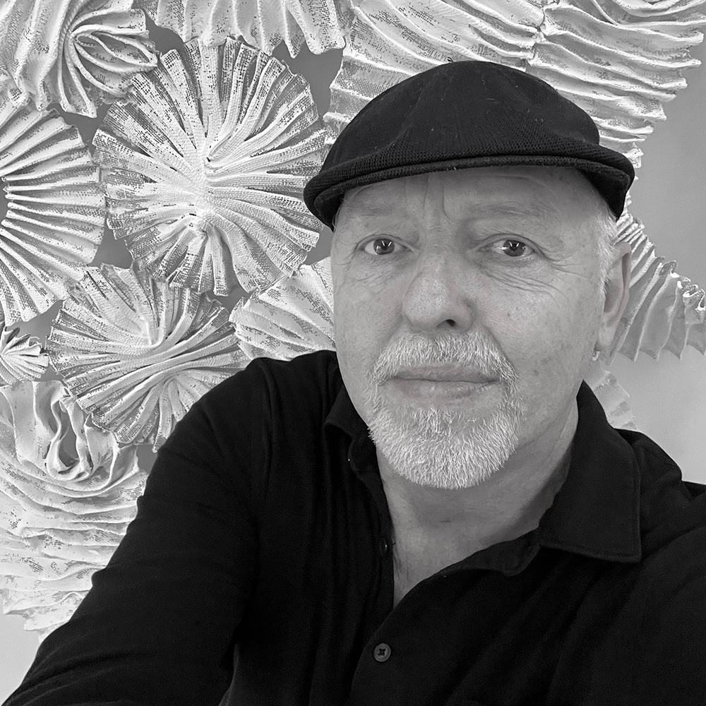 a black and white portrait of an older white man wearing a black polo shirt and black cap