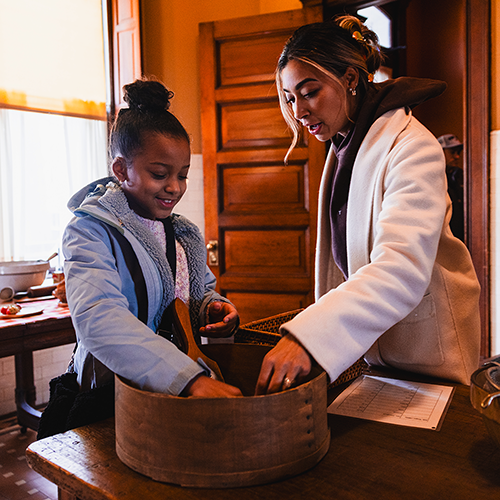 A woman and a child explore the kitchen of a historic home
