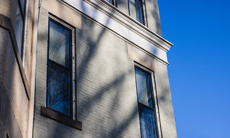 a brick wall of a home painted a light green/gray color