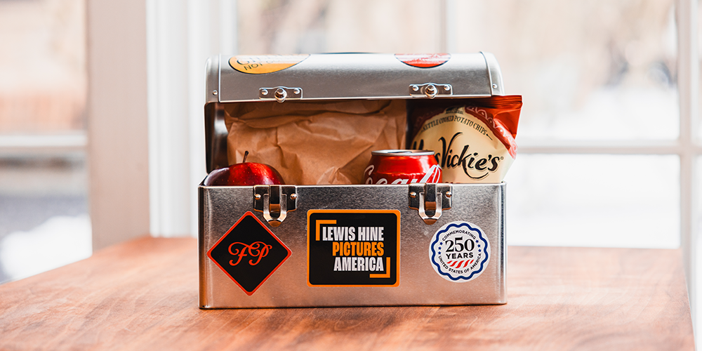 A vintage-style metal lunch box adorned with stickers and filled with food