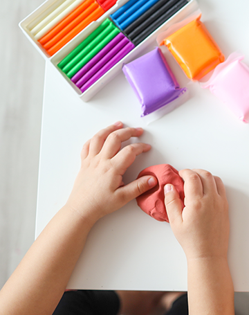 A pair of hands manipulating colorful clay